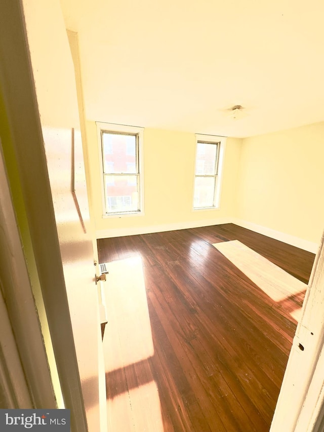 empty room with a wealth of natural light and hardwood / wood-style flooring