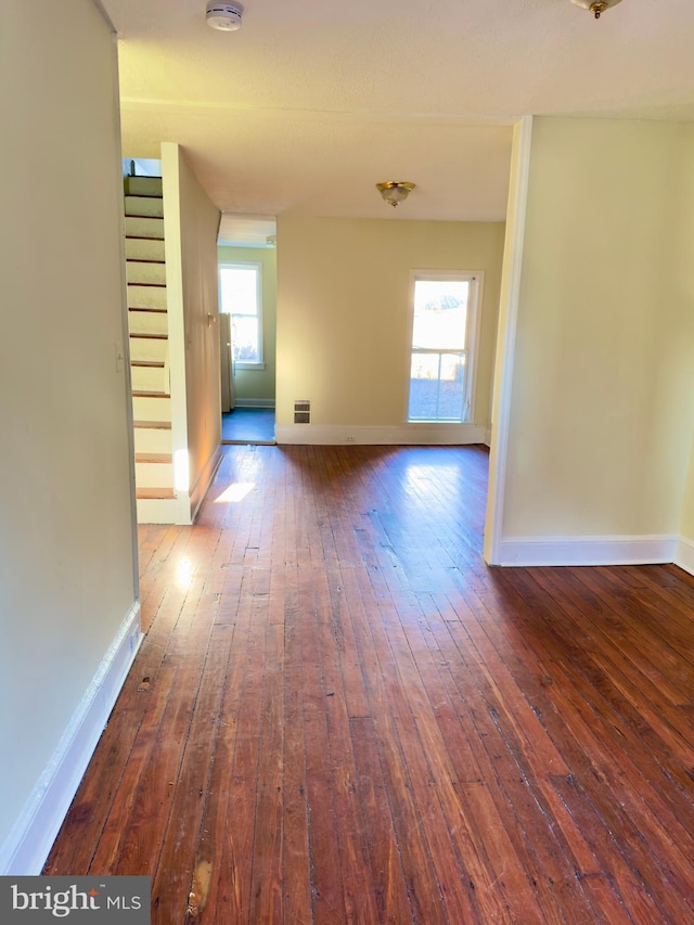 spare room with dark hardwood / wood-style flooring and plenty of natural light