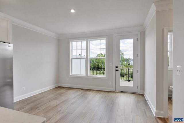 doorway to outside with light hardwood / wood-style flooring, a wealth of natural light, and ornamental molding