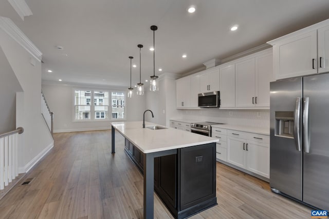 kitchen featuring sink, decorative light fixtures, a center island with sink, white cabinets, and appliances with stainless steel finishes