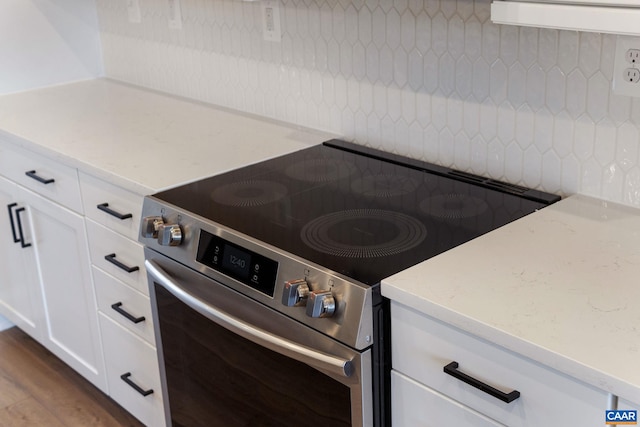 kitchen with white cabinets, light stone countertops, wood-type flooring, and high end range