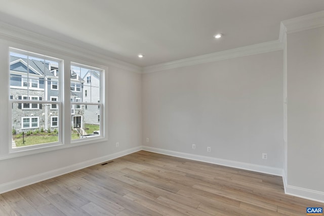 spare room featuring a wealth of natural light, light hardwood / wood-style flooring, and ornamental molding