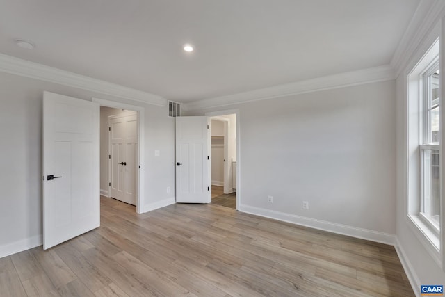 unfurnished bedroom featuring light wood-type flooring, multiple windows, and ornamental molding