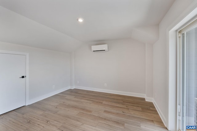 additional living space featuring a wall mounted air conditioner, light hardwood / wood-style floors, and vaulted ceiling