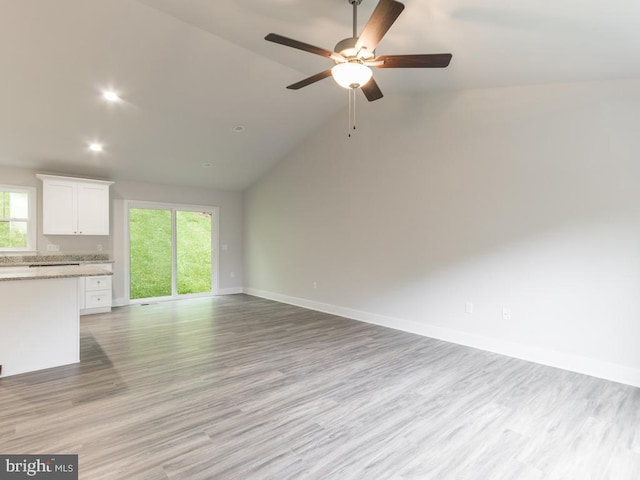 unfurnished living room featuring ceiling fan, light hardwood / wood-style flooring, high vaulted ceiling, and a healthy amount of sunlight