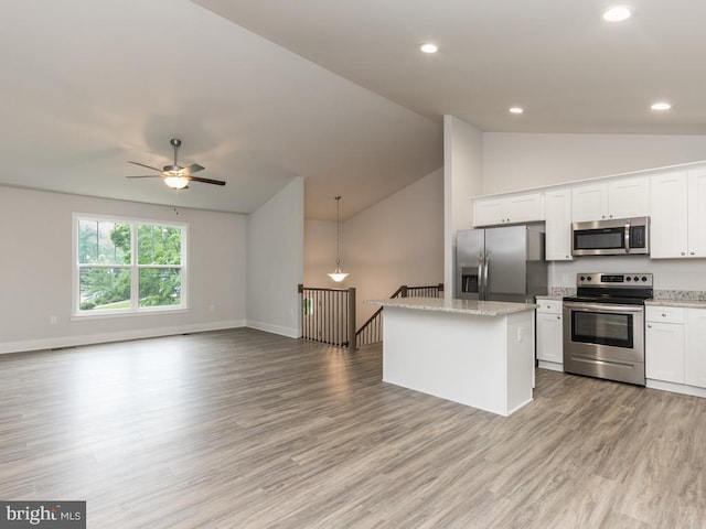 kitchen with appliances with stainless steel finishes, a center island, white cabinetry, and vaulted ceiling