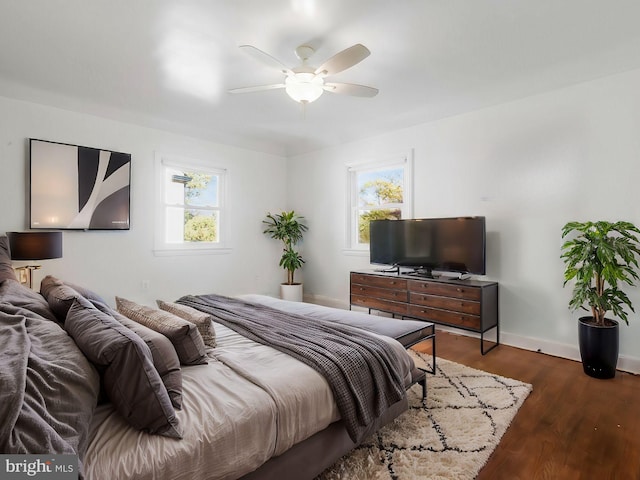 bedroom featuring multiple windows, ceiling fan, and dark hardwood / wood-style flooring