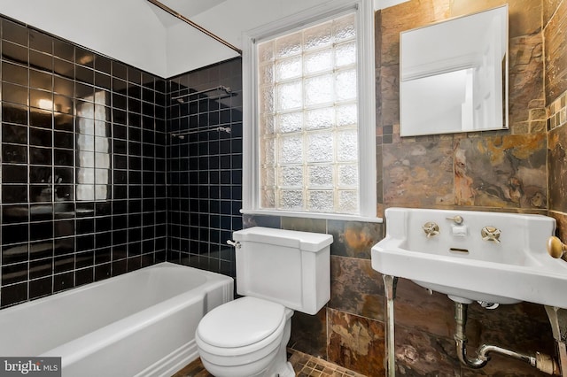 full bathroom with sink, tile patterned flooring, tiled shower / bath combo, toilet, and tile walls