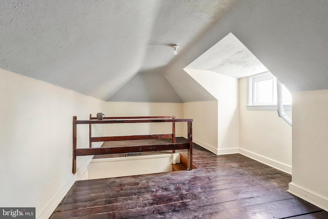 additional living space with a textured ceiling, dark hardwood / wood-style flooring, and lofted ceiling