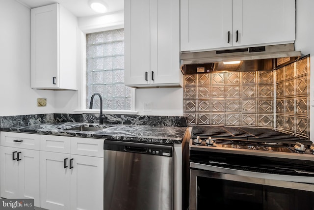 kitchen featuring stainless steel appliances, white cabinetry, dark stone countertops, and sink