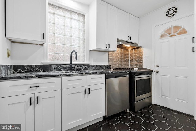 kitchen featuring dark tile patterned floors, backsplash, dark stone countertops, white cabinets, and appliances with stainless steel finishes