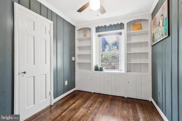 interior space featuring ceiling fan, built in features, dark wood-type flooring, and ornamental molding