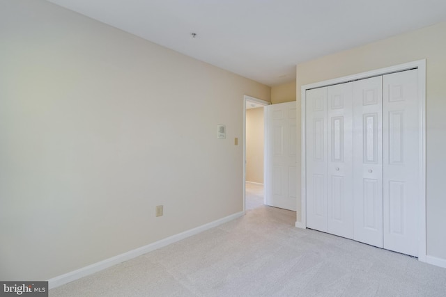 unfurnished bedroom featuring light colored carpet and a closet