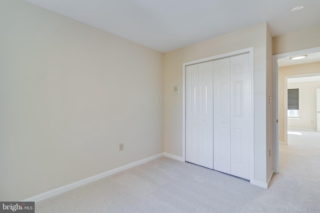 unfurnished bedroom featuring light carpet and a closet