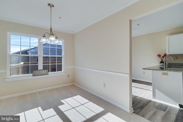 unfurnished dining area with sink, an inviting chandelier, light hardwood / wood-style floors, and ornamental molding