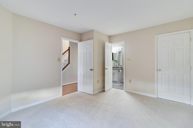 unfurnished bedroom with connected bathroom and light colored carpet