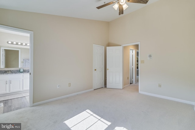 unfurnished bedroom featuring ensuite bathroom, ceiling fan, light colored carpet, and sink