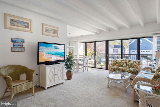 living room featuring carpet flooring, a textured ceiling, a healthy amount of sunlight, and a notable chandelier