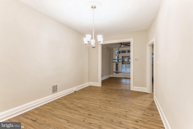 unfurnished dining area with hardwood / wood-style flooring and ceiling fan with notable chandelier