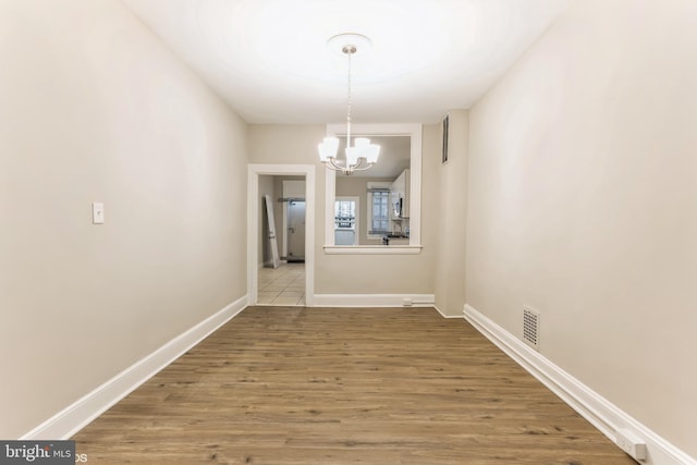 unfurnished dining area featuring light hardwood / wood-style flooring and a notable chandelier