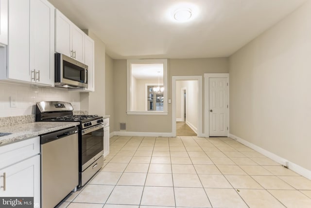 kitchen with light stone countertops, white cabinets, light tile patterned flooring, and appliances with stainless steel finishes