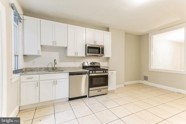 kitchen with light stone counters, white cabinetry, sink, and appliances with stainless steel finishes