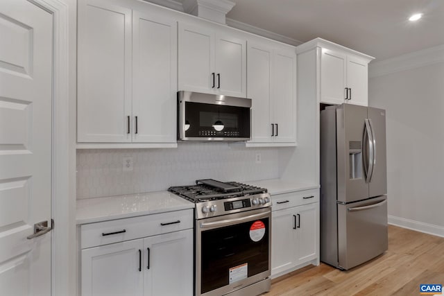 kitchen with light wood-type flooring, white cabinetry, crown molding, and appliances with stainless steel finishes