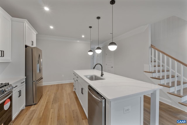 kitchen featuring a kitchen island with sink, sink, light wood-type flooring, appliances with stainless steel finishes, and white cabinetry