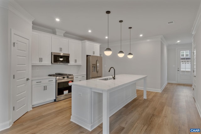 kitchen with a kitchen island with sink, sink, decorative light fixtures, light hardwood / wood-style floors, and stainless steel appliances