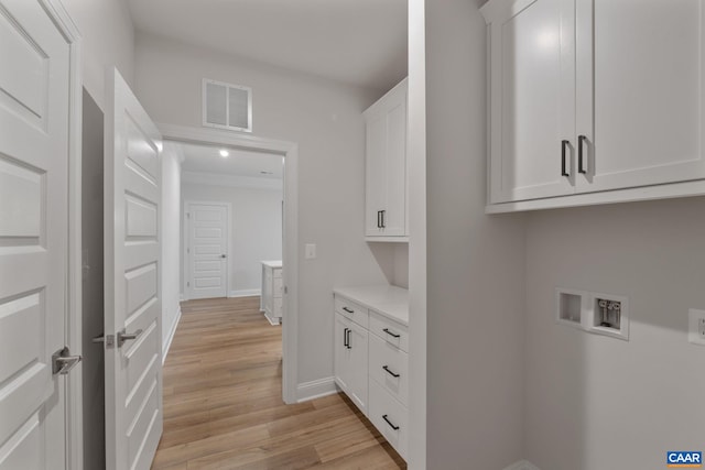 clothes washing area with cabinets, hookup for a washing machine, and light hardwood / wood-style floors