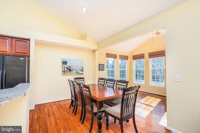 dining space featuring light wood finished floors, baseboards, and lofted ceiling