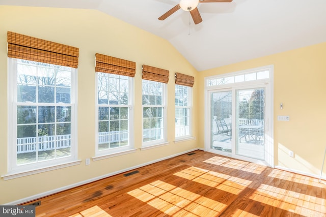 unfurnished sunroom with vaulted ceiling, a ceiling fan, and visible vents