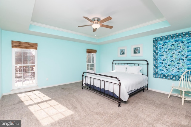 carpeted bedroom with a raised ceiling, crown molding, baseboards, and ceiling fan