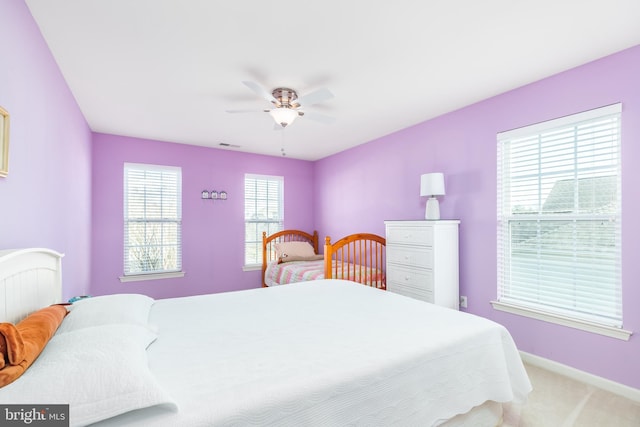 bedroom featuring visible vents, light colored carpet, a ceiling fan, and baseboards