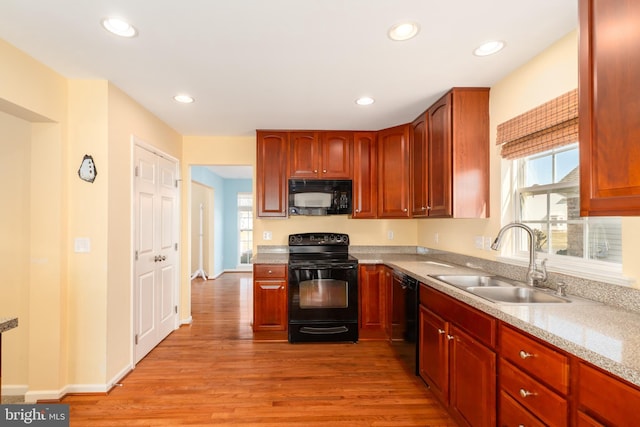 kitchen featuring a sink, plenty of natural light, black appliances, and light wood finished floors