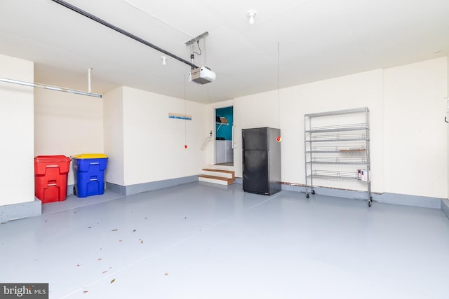 garage featuring baseboards, a garage door opener, and freestanding refrigerator