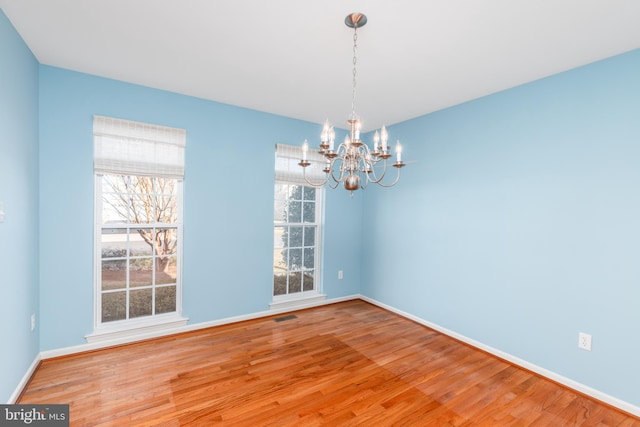 unfurnished dining area featuring wood finished floors, baseboards, a chandelier, and a healthy amount of sunlight