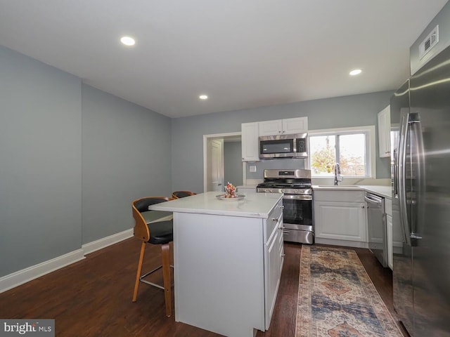 kitchen with white cabinetry, sink, dark hardwood / wood-style flooring, a kitchen island, and appliances with stainless steel finishes