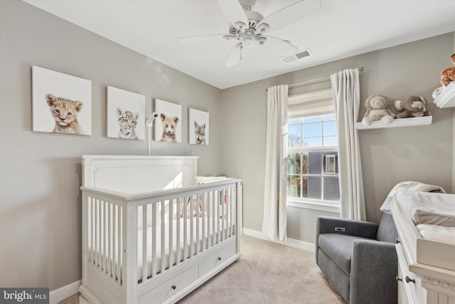 carpeted bedroom with ceiling fan and a crib