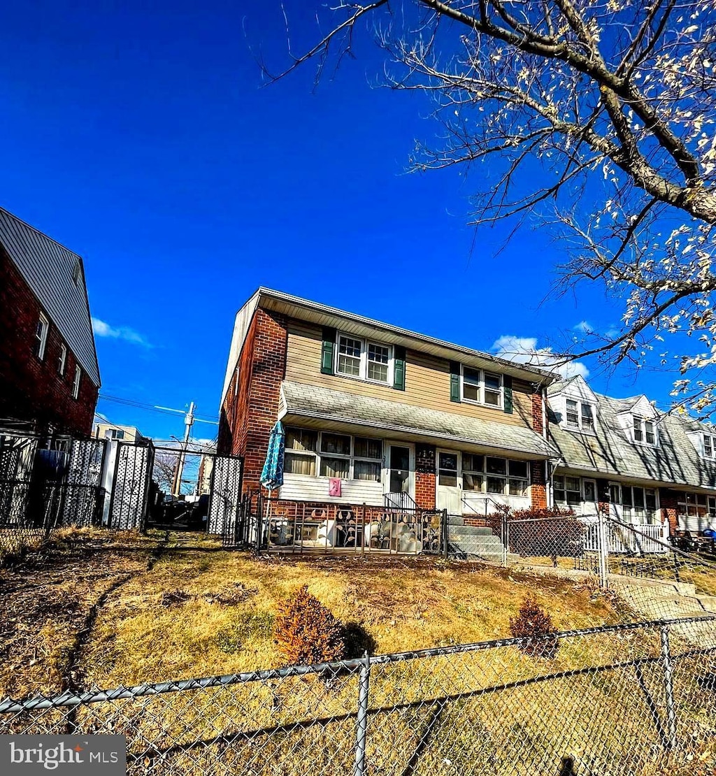 view of front facade featuring brick siding and a fenced front yard