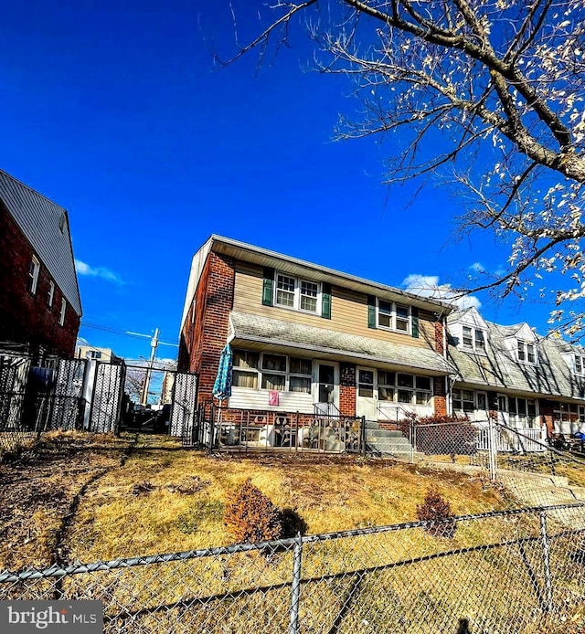 view of front facade featuring brick siding and a fenced front yard