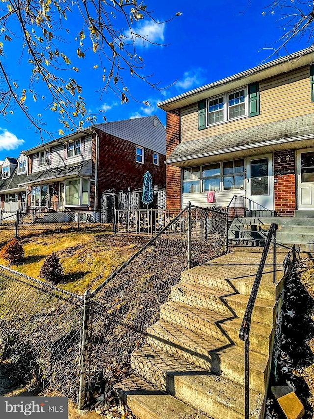 rear view of property featuring a fenced front yard and brick siding