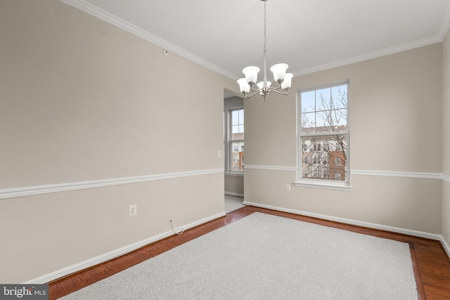 empty room featuring baseboards, ornamental molding, wood finished floors, and an inviting chandelier