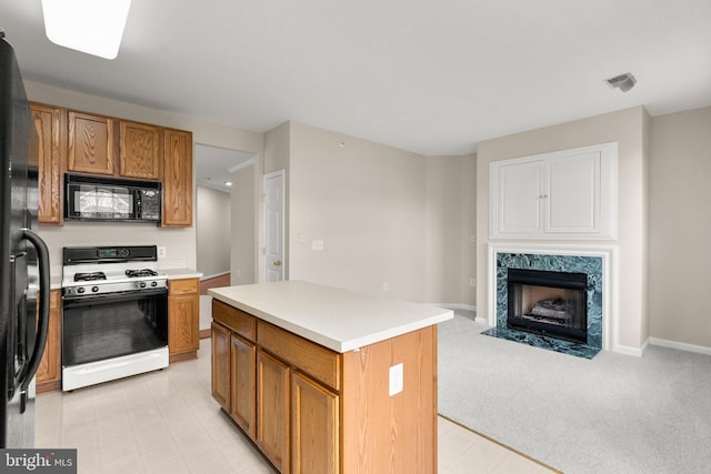 kitchen featuring light countertops, visible vents, brown cabinetry, a high end fireplace, and black appliances