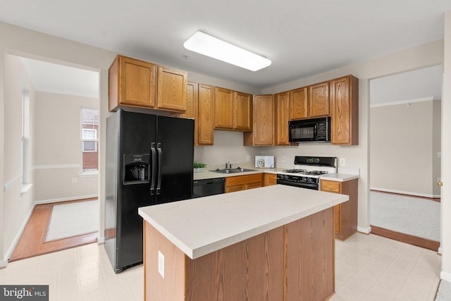 kitchen featuring light floors, light countertops, a sink, a kitchen island, and black appliances