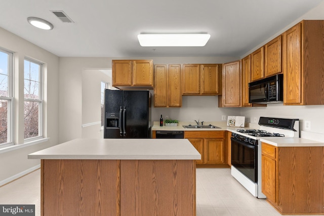 kitchen featuring light countertops, a sink, visible vents, and black appliances