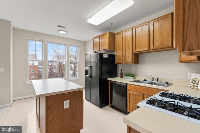 kitchen with light floors, a sink, visible vents, light countertops, and black appliances