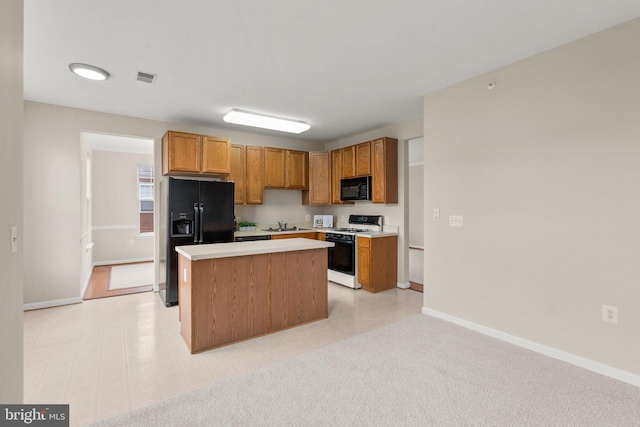 kitchen with light carpet, visible vents, light countertops, a center island, and black appliances