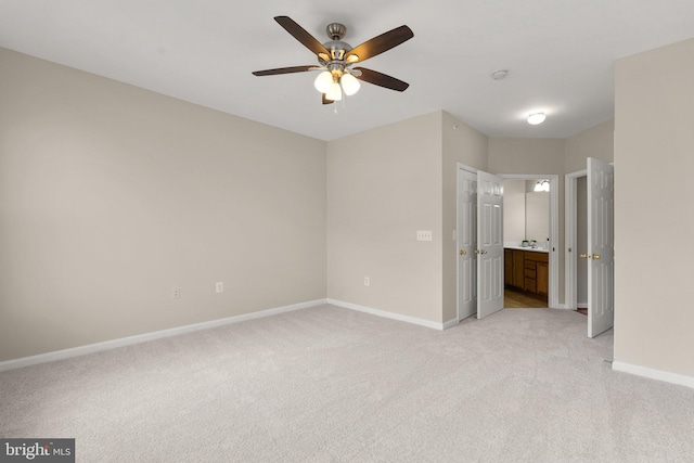 unfurnished bedroom with light carpet, ceiling fan, baseboards, and connected bathroom