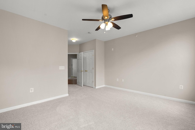 unfurnished room with baseboards, a ceiling fan, and light colored carpet